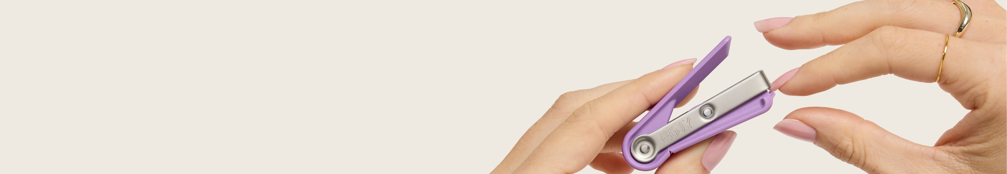 Close-up of a person using a lilac EDJY fingernail cutter to trim their manicured fingernails. 